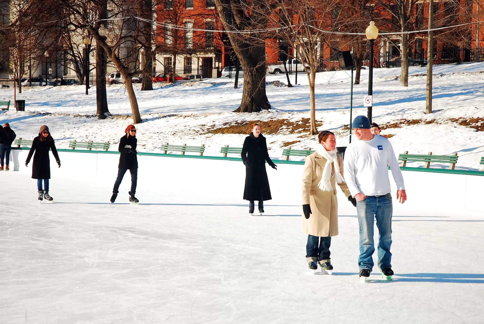 A couple enjoys skating on the frozen Frog Pond in Boston Common on a sunny winter day in Boston, Massachusetts.