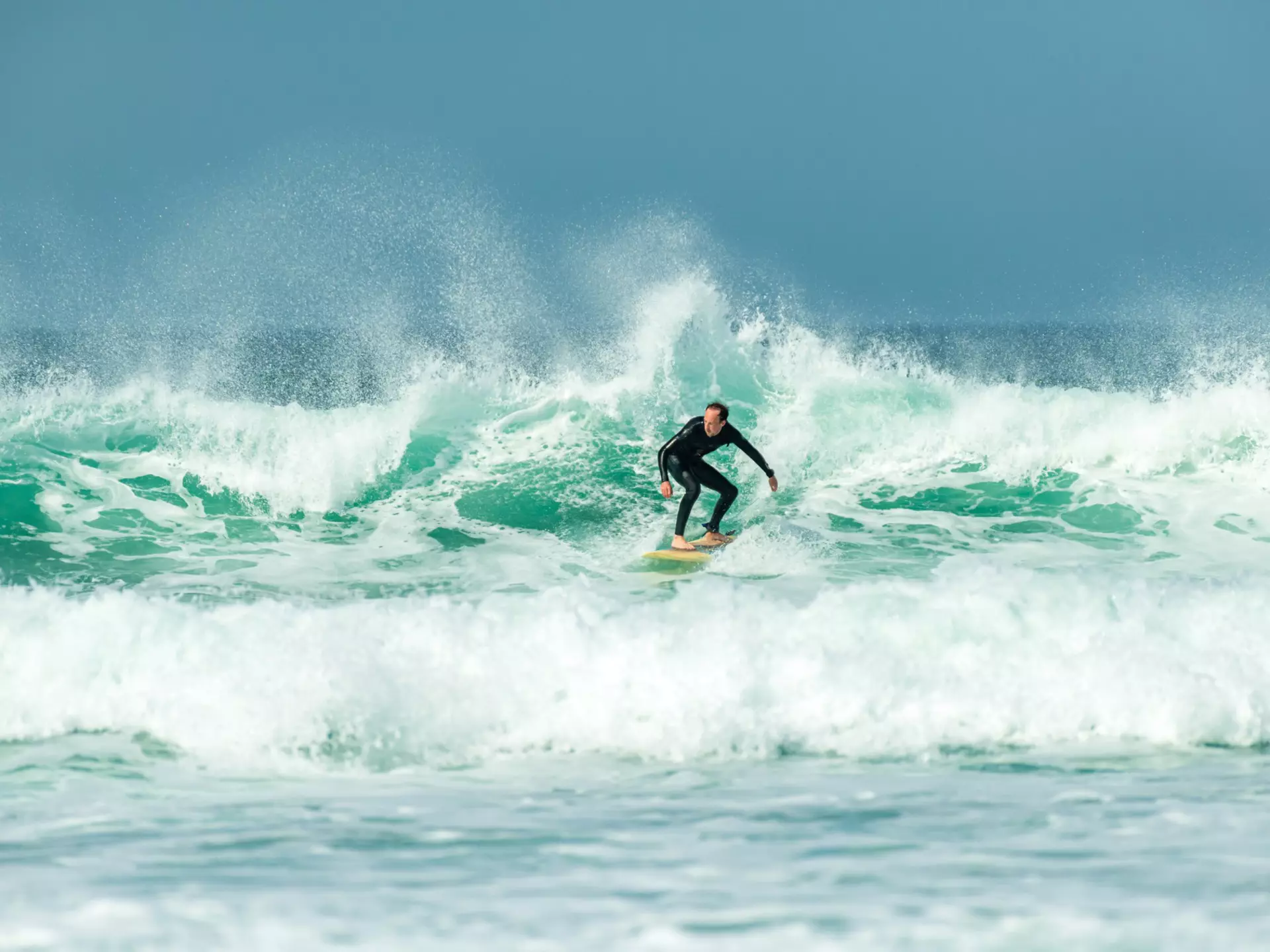 A surfer on big waves at Fistral Beach, Newquay, Cornwall, UK.