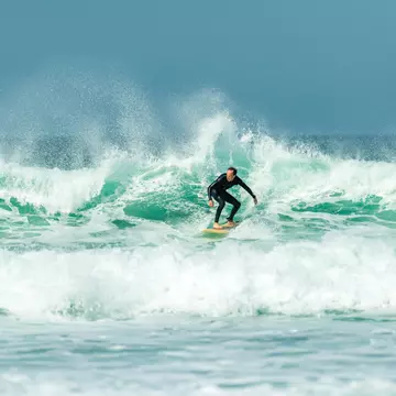 A surfer on big waves at Fistral Beach, Newquay, Cornwall, UK.