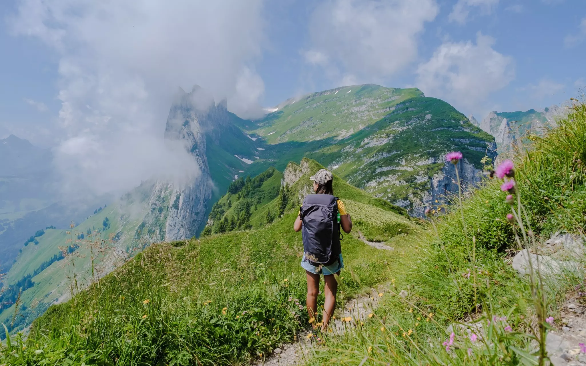 Woman hiking in the Swiss Alps mountains during summer vacation with a backpack and hiking boots. woman walking on the Saxer Lucke path a popular hiking trail in Switzerland