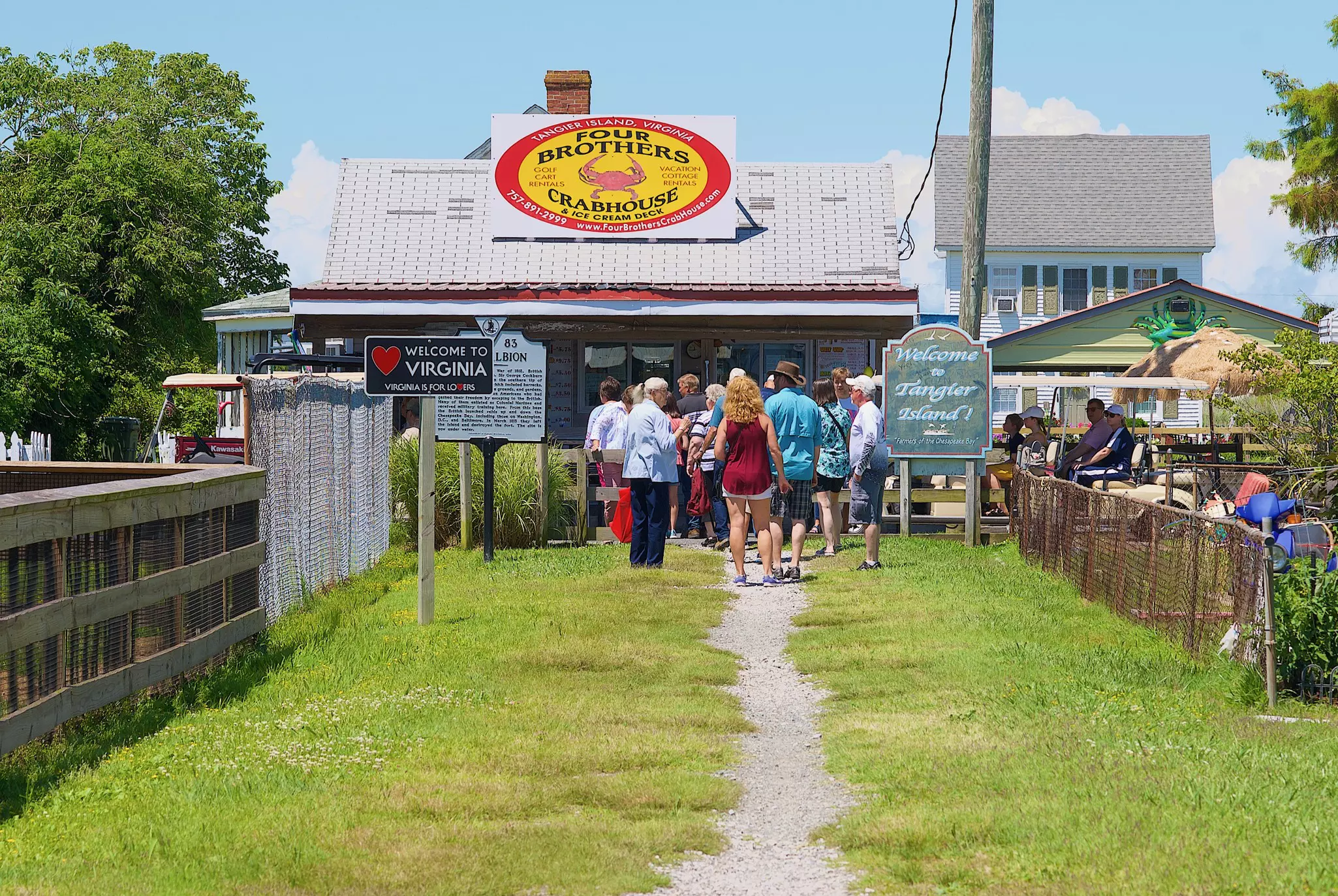 Newly arrived tourists walk past the “Welcome to Virginia” and “Welcome to Tangier Island!” signs on their way to Main Street in this popular Chesapeake Bay tourist destination.