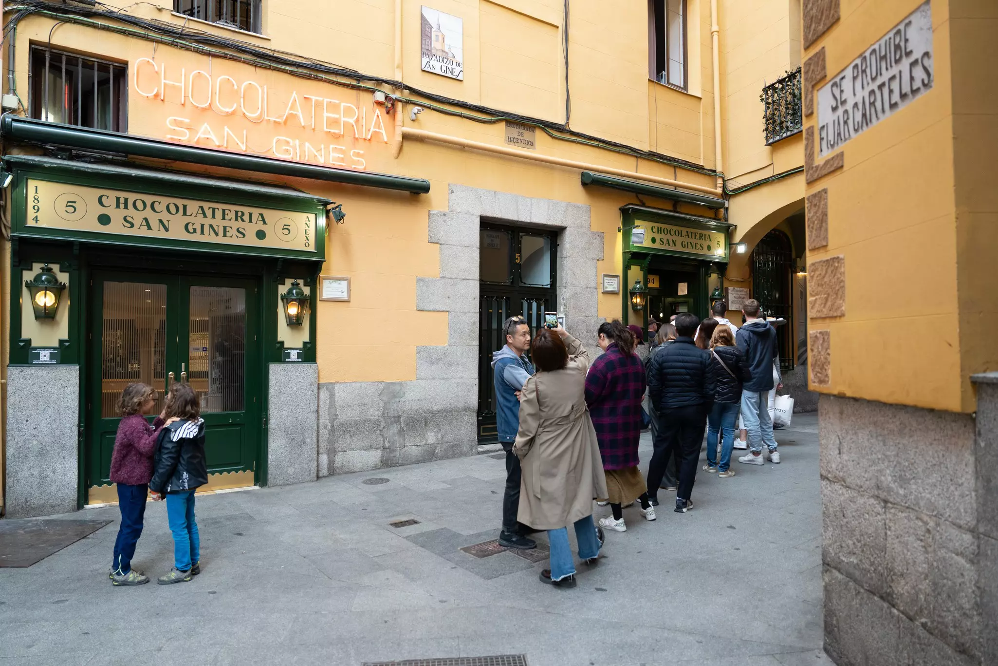 People in an alleyway outside a chocolate shop in Spain.