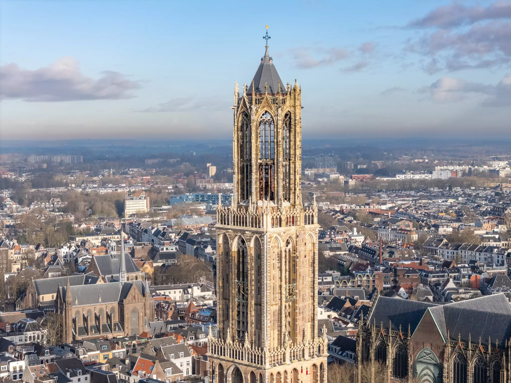An ornate church bell tower rising high above the roofs of a city.