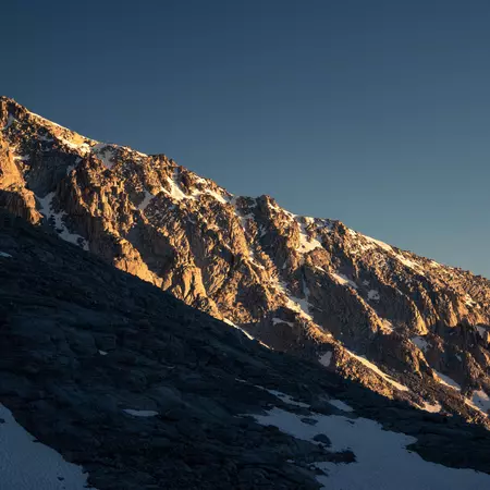 Ripples of rock in a cliff face glow in the setting sun.