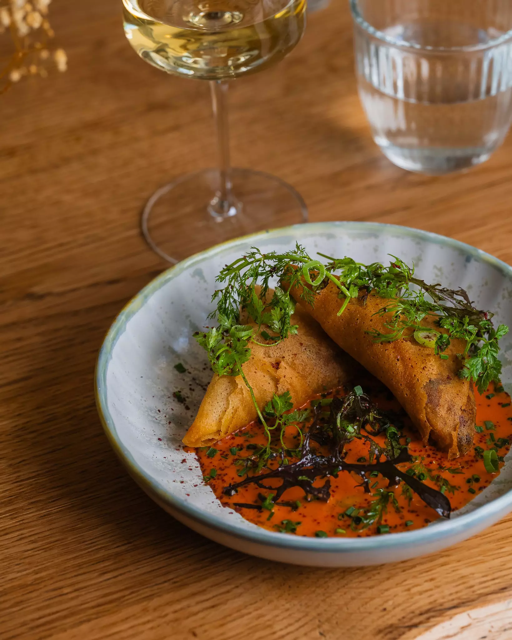 Two samosas in a dish with sauce.
