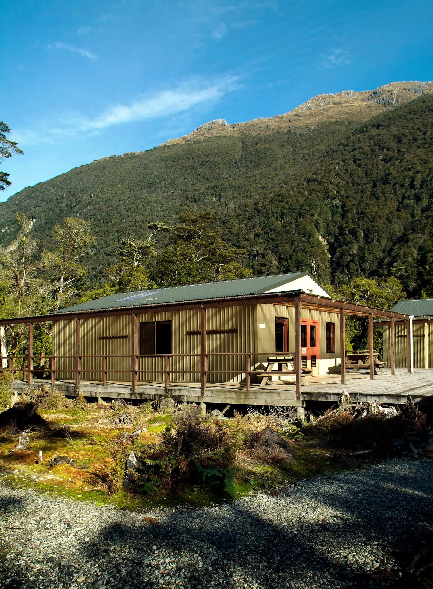 A basic hut on a hiking trail at the foot of a large hill.