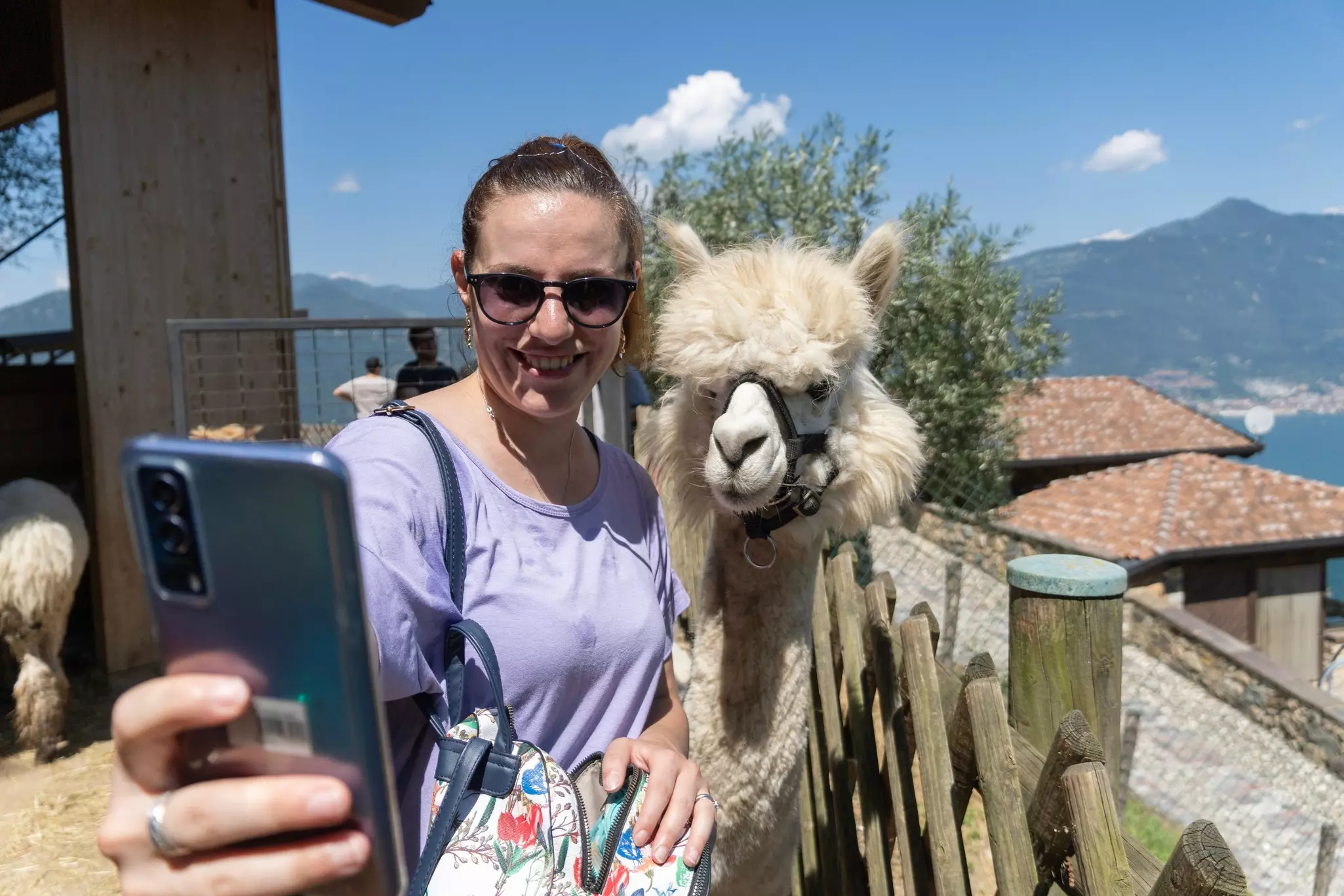 Smiling woman takes a selfie with a white alpaca in Peru