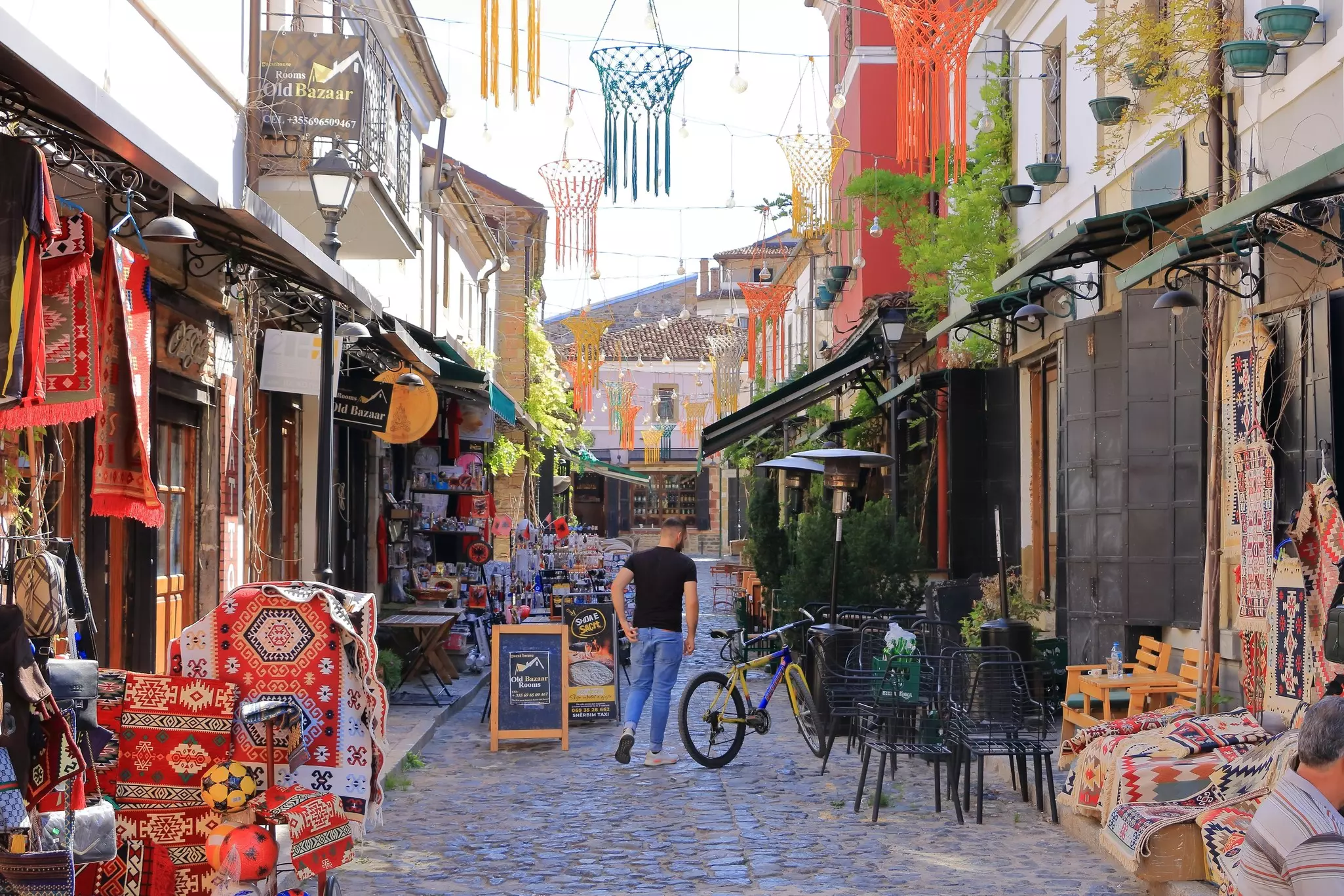 A man walks down a street filled with shops selling rugs, textiles and other goods in open stalls at the historic bazaar of Korça, Albania