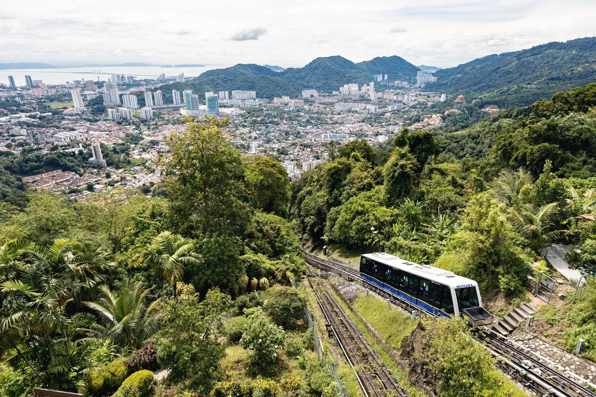 A wide view of a funicular ascending a hill above a city.