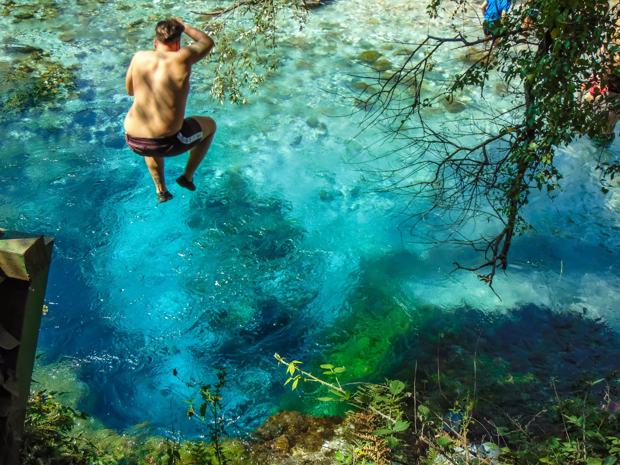 Young man diving into Blue Eye (syri i kalter) spring in Albania.