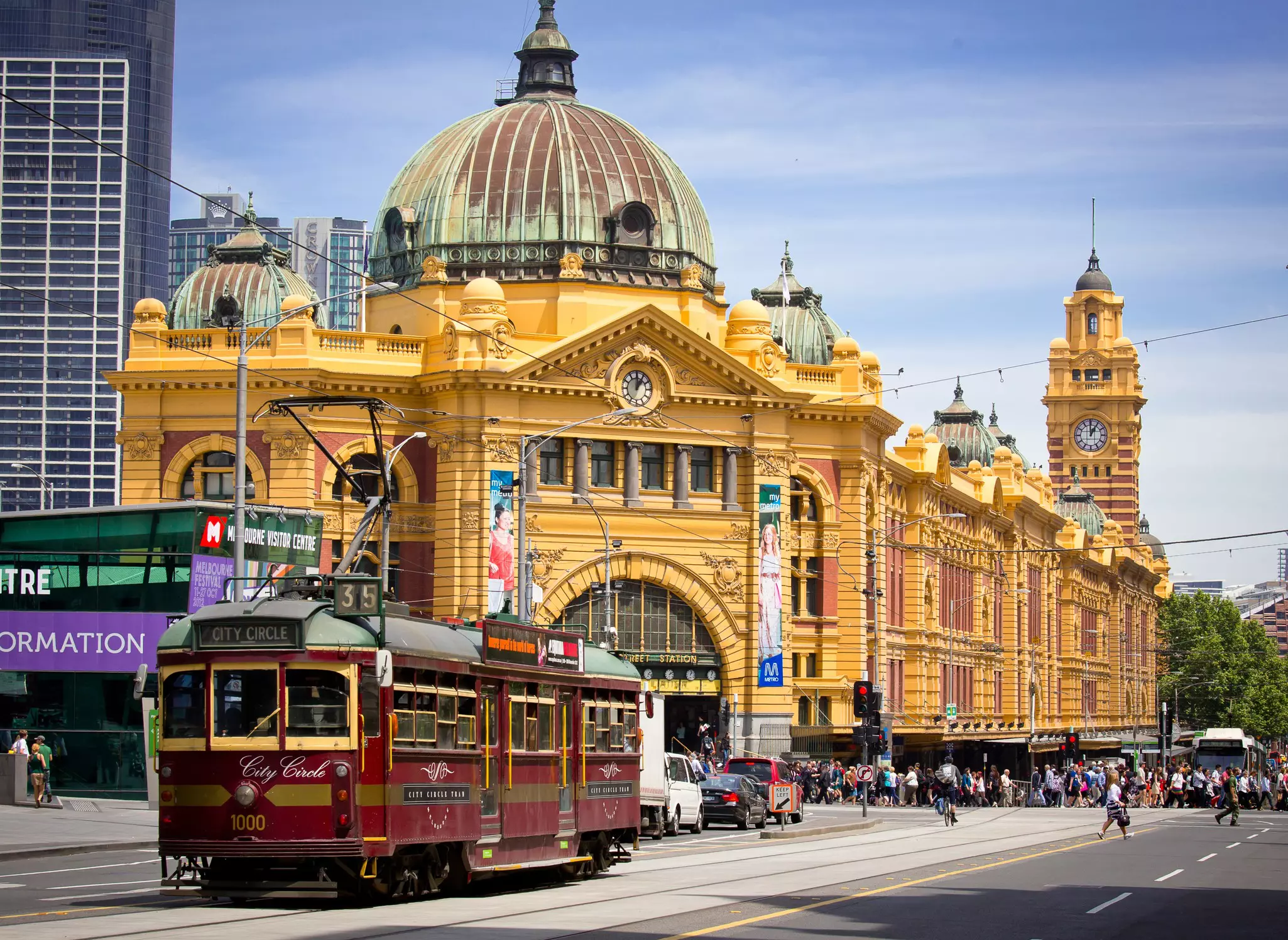 A free City Circle tram passes Flinders Street Station in Melbourne with cars and people in the city nearby