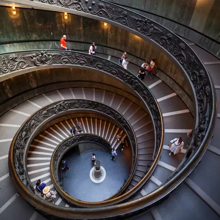 Tourists on a spiraling staircase in the Vatican Museums.