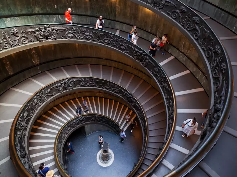 Tourists on a spiraling staircase in the Vatican Museums.
