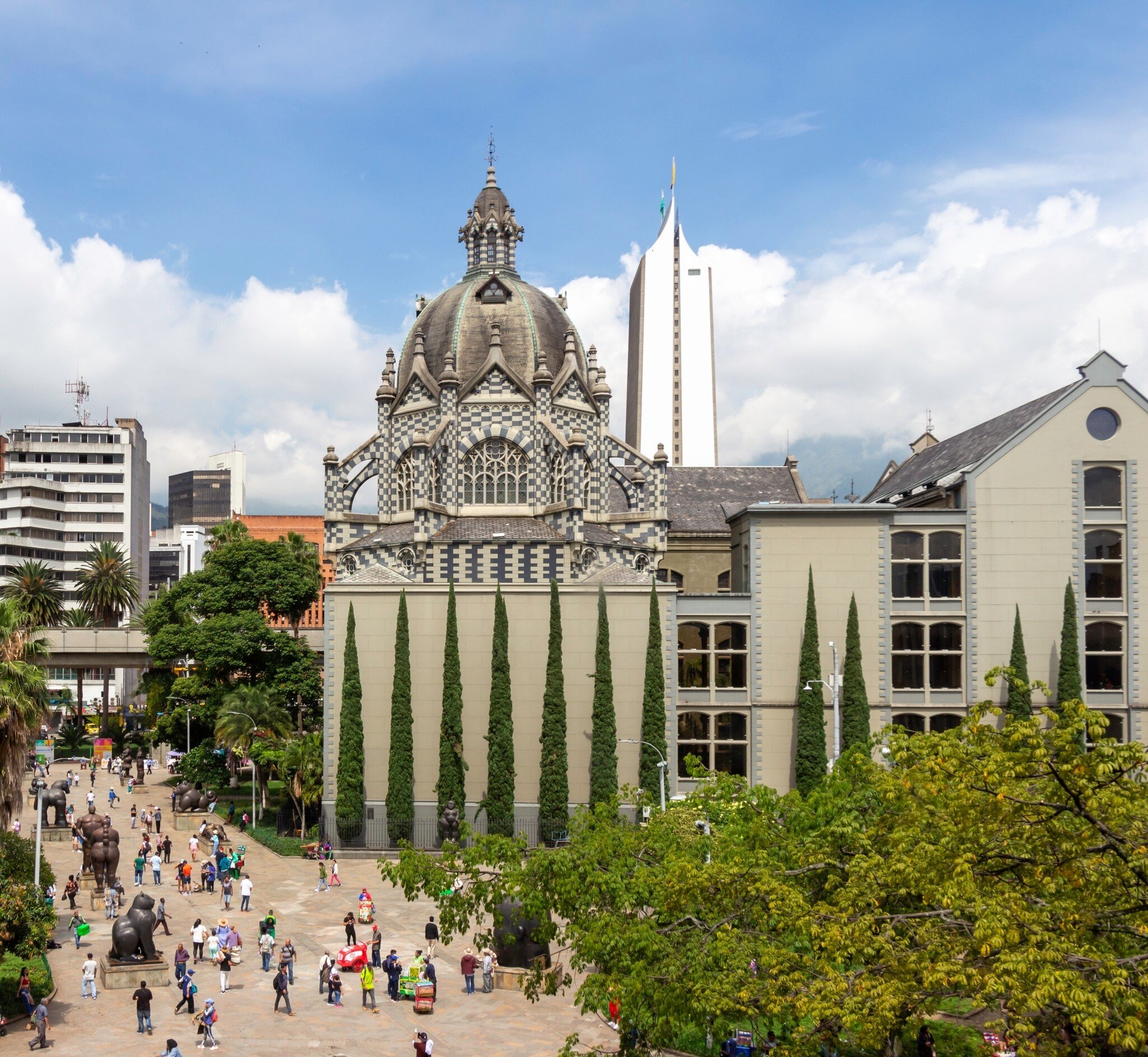 Palacio de la Cultura, Medellín: black-and-white checkered stone dome above cypresses, Botero sculptures in the plaza