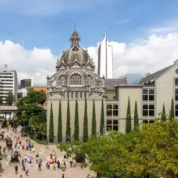 Palacio de la Cultura, Medellín: black-and-white checkered stone dome above cypresses, Botero sculptures in the plaza