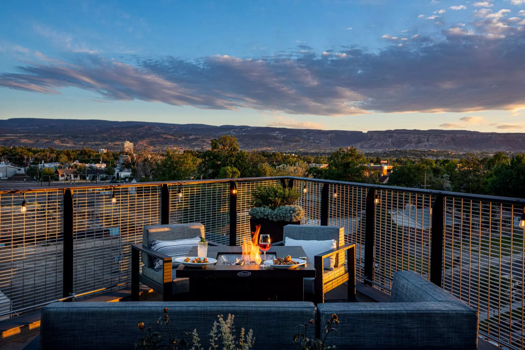 Seats around a patio fire pit with a mesa in the distance