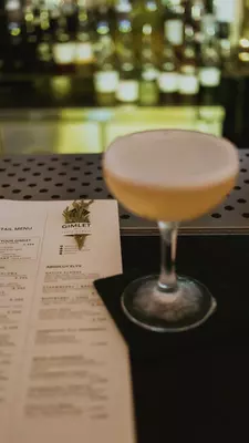 a gimlet next to a bar menu