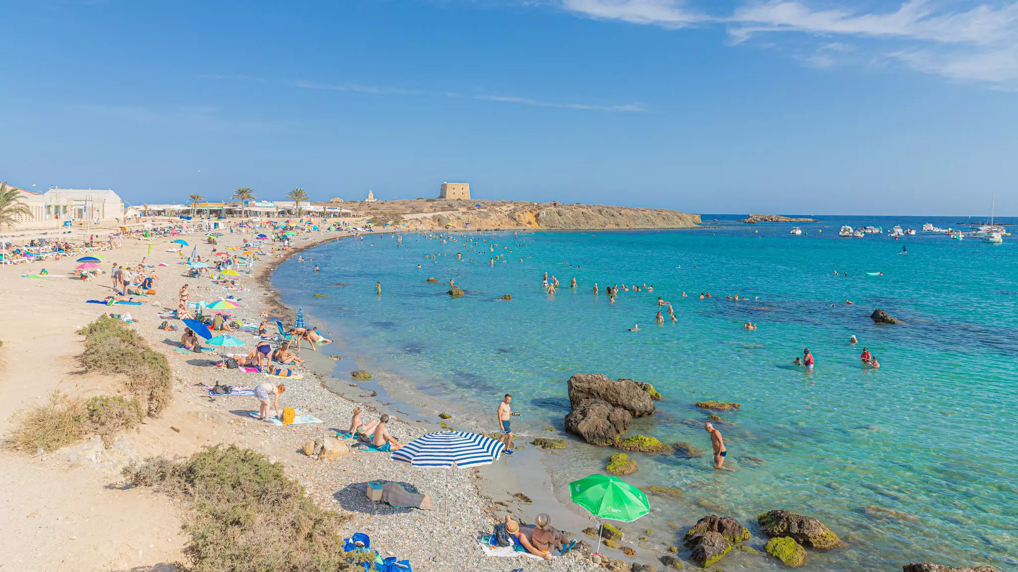 People on a beach by turquoise water.