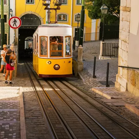 A yellow funicular car travels up a steep hill