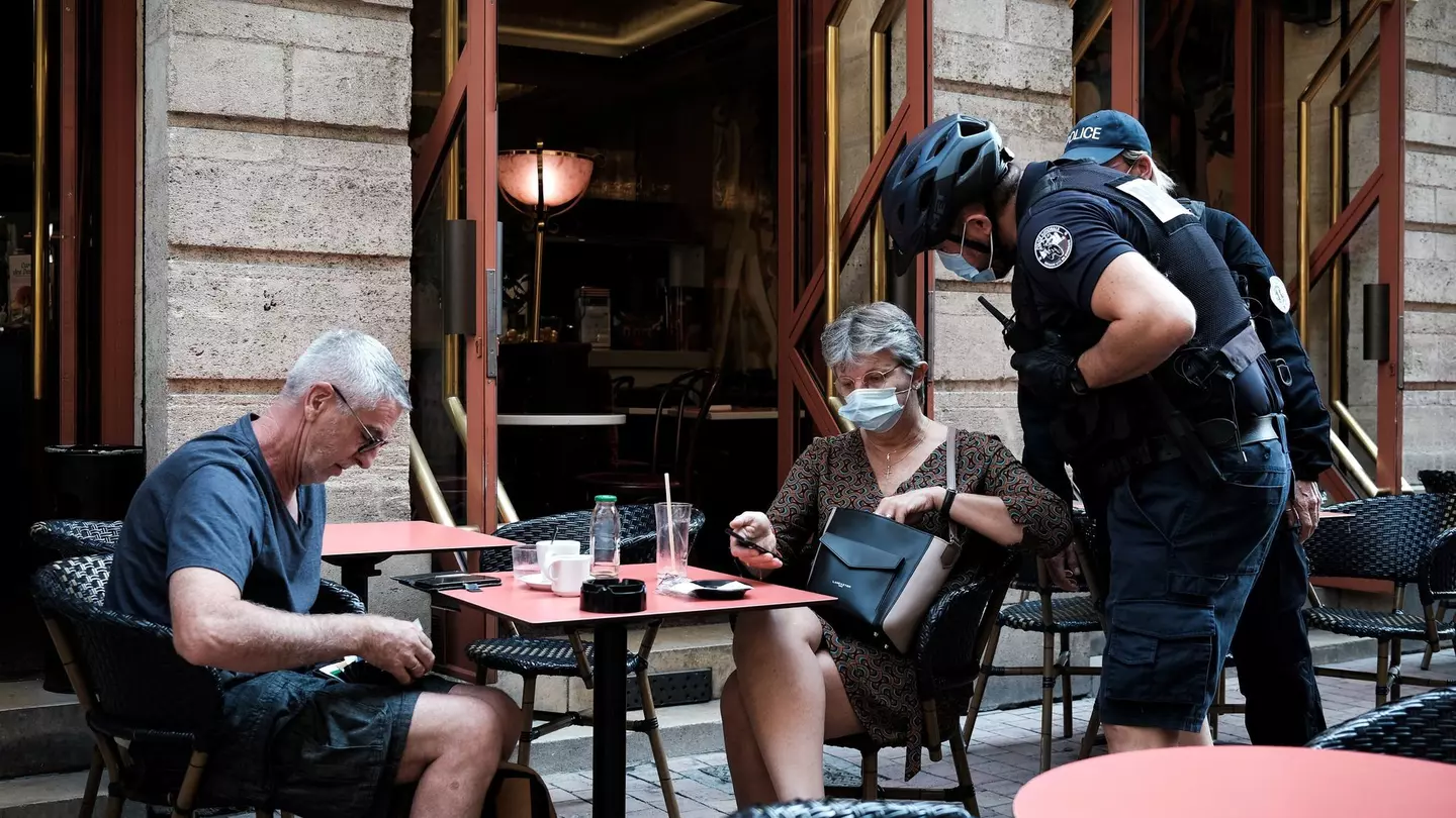 A policeman checks the health pass of a customer at a bar in Bordeaux.