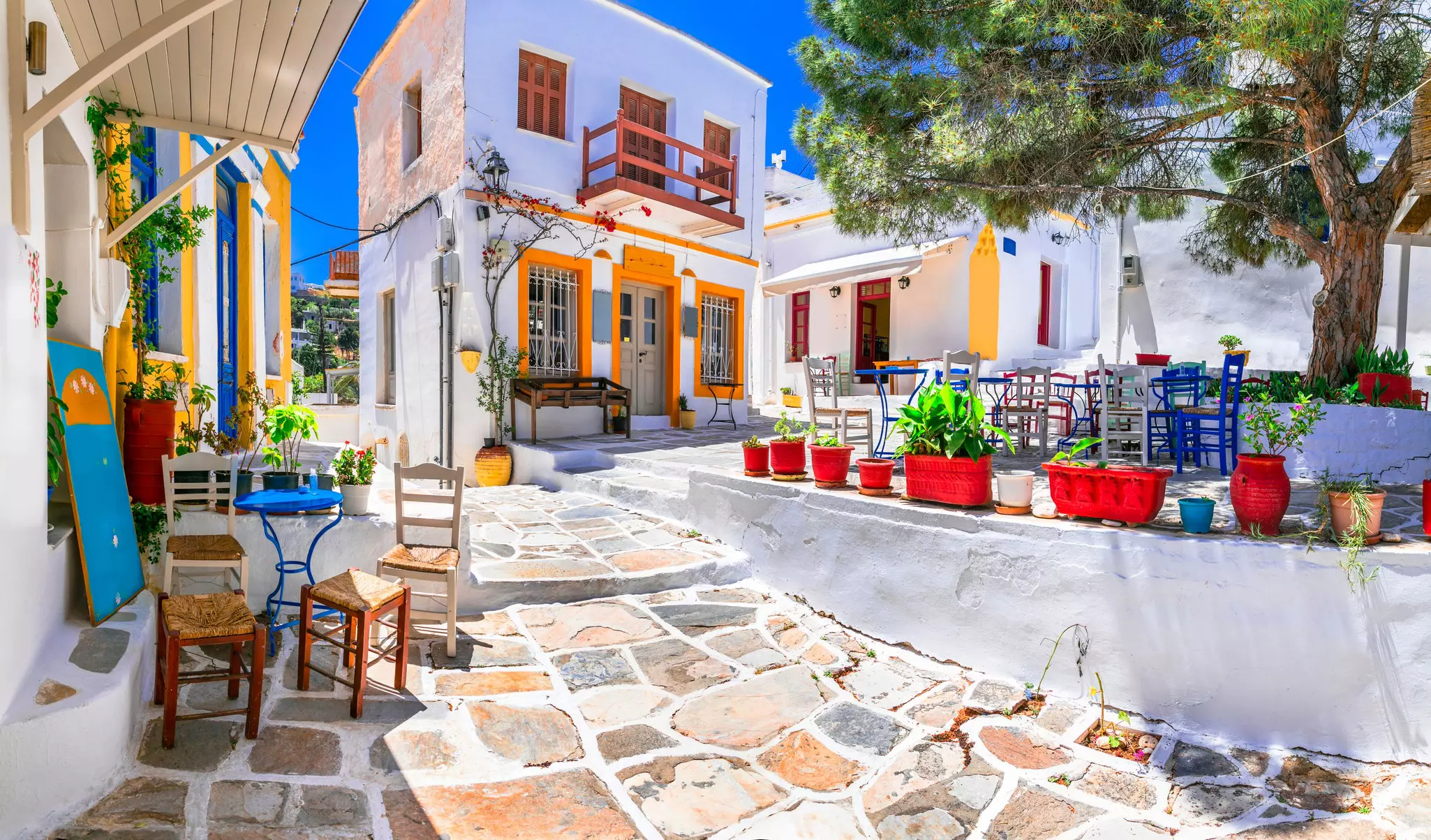 White buildings with colorful planters and chairs outside in a Greek village on Paros Island