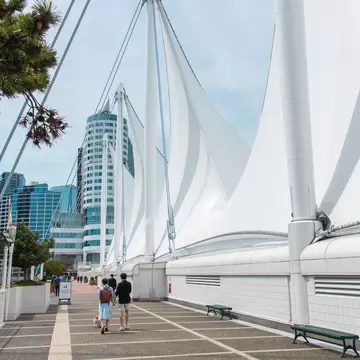 People walking by Canada Place, a multi-purpose facility building situated on the Burrard Inlet in Vancouver, BC, Canada.