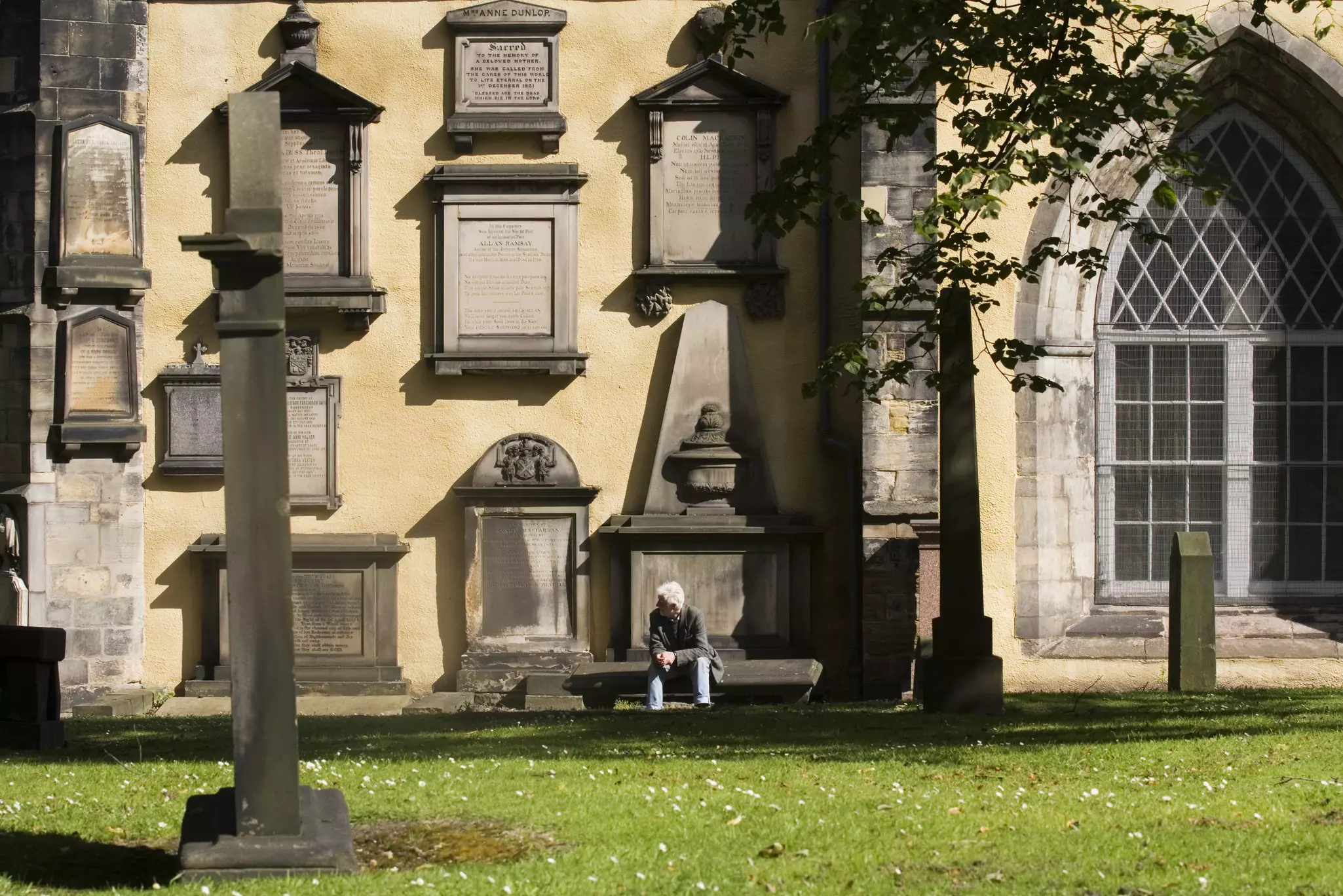 A man rests on a bench in front of a stone building