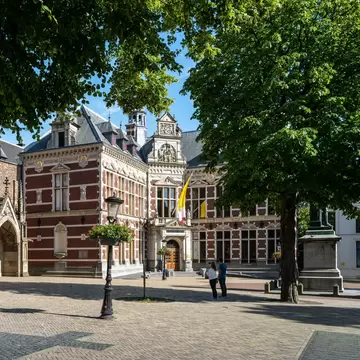 View of the Utrecht University Hall (Academiegebouw) at Domplein with monument of Jan Van Nassau in the foreground on a sunny day.