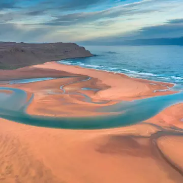 Aerial drone view of icelandic Raudasandur beach with azure water streams and yellow sand