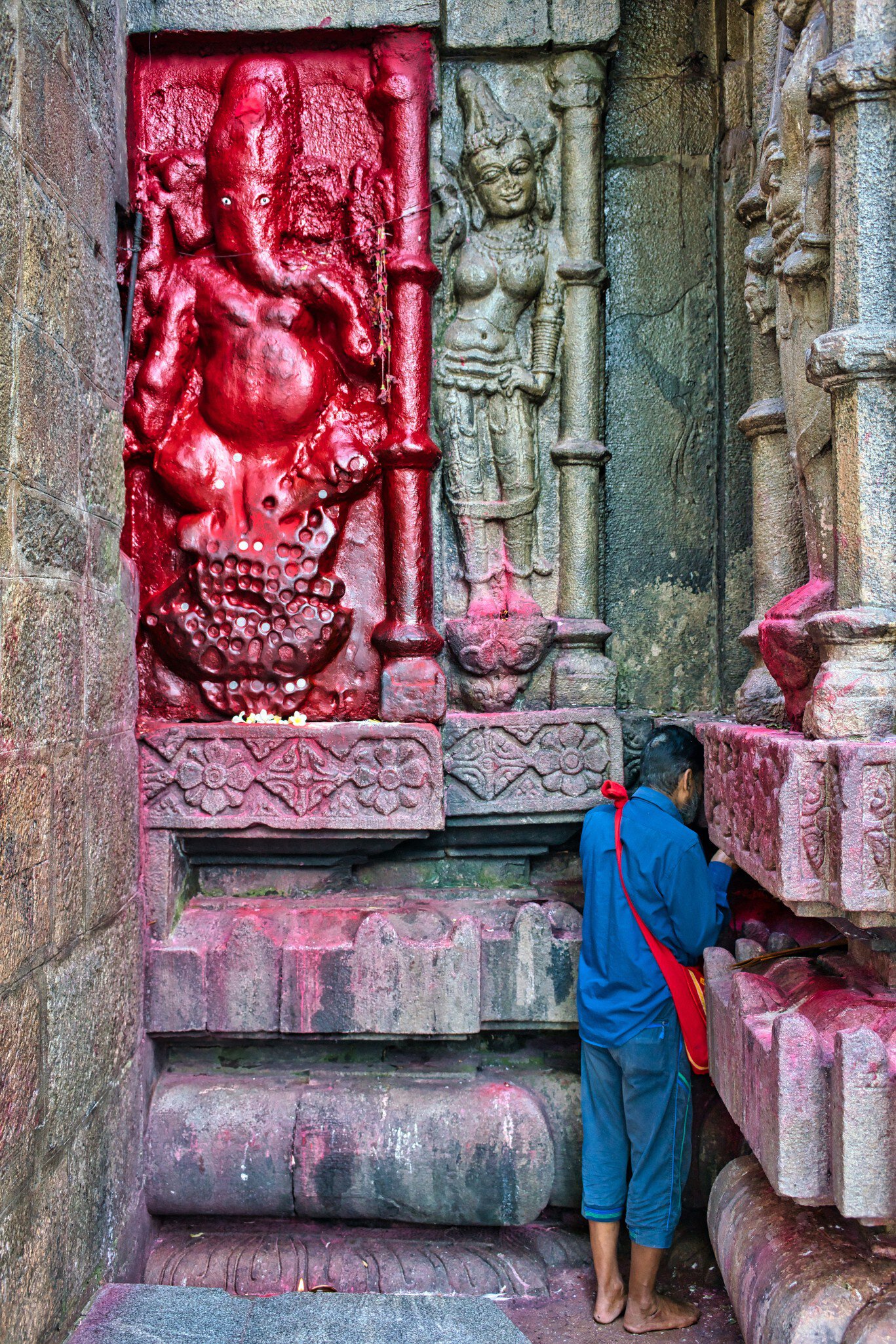A man praying at old antique statues made in stone, on the walls inside Kamakhya Temple, where people worship mother goddess Kamakhya, in Guwahat, India.