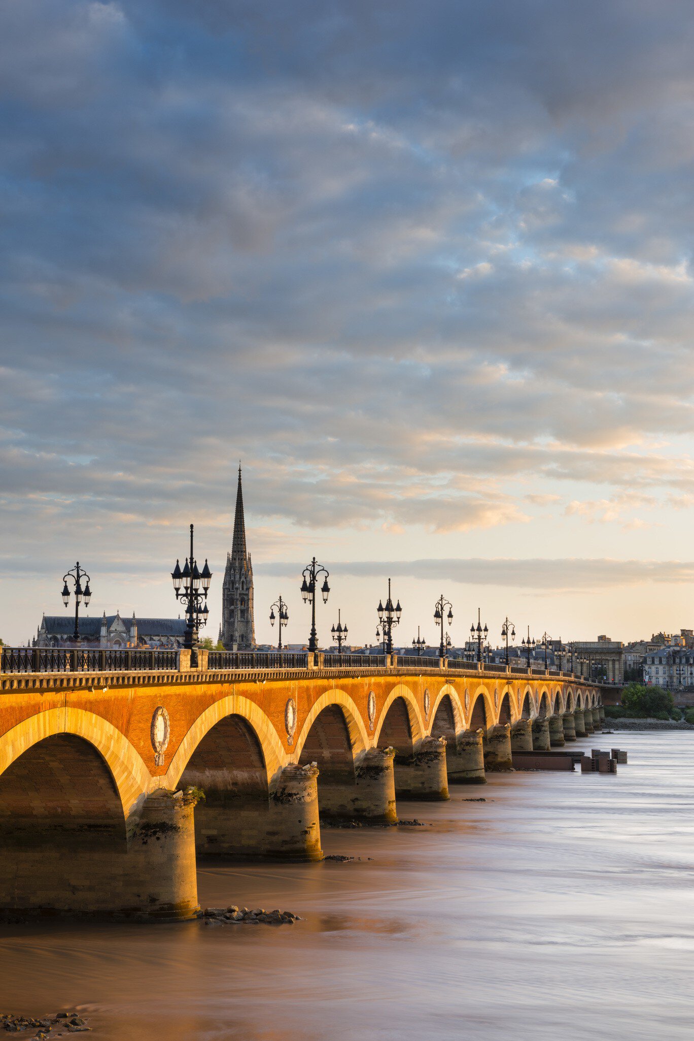Pont de Pierre bridge over the Garonne with the spire of Eglise St-Michel in background. Bordeaux, France.