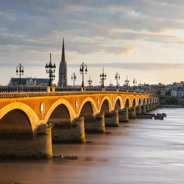 Pont de Pierre bridge over the Garonne with the spire of Eglise St-Michel in background. Bordeaux, France.