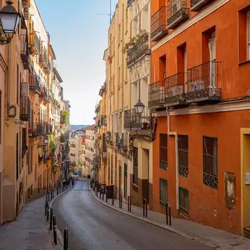 A narrow, curved city street going downhill, lined by colorful buildings.