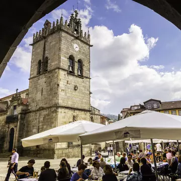 View of the Igreja de Nossa Senhora da Oliveira on the Largo da Oliveira in Guimarães, Portugal, with visitors seated in outdoor restaurants.
