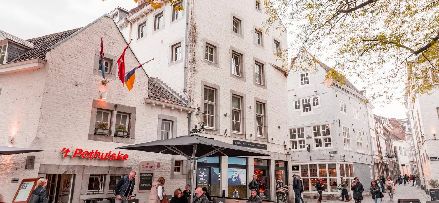 A pedestrianized cobblestone street lined with restaurants, cafes and shops.