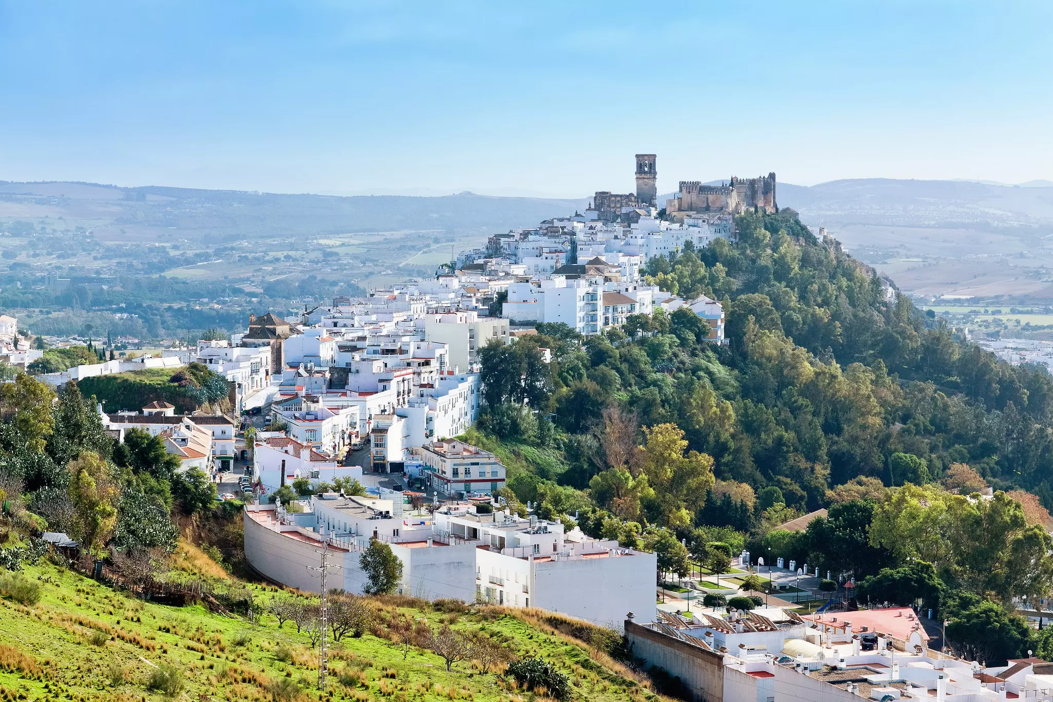 The white buildings of Arcos de la Frontera sit on top of a sandstone ridge.