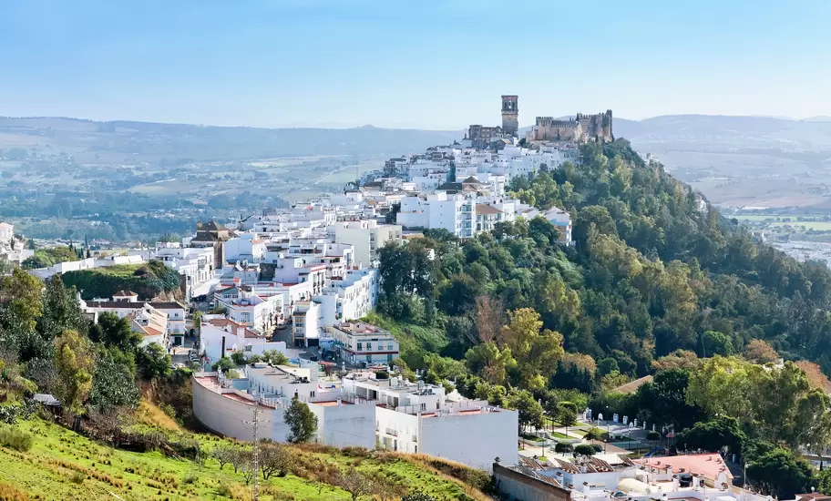 The white buildings of Arcos de la Frontera sit on top of a sandstone ridge.