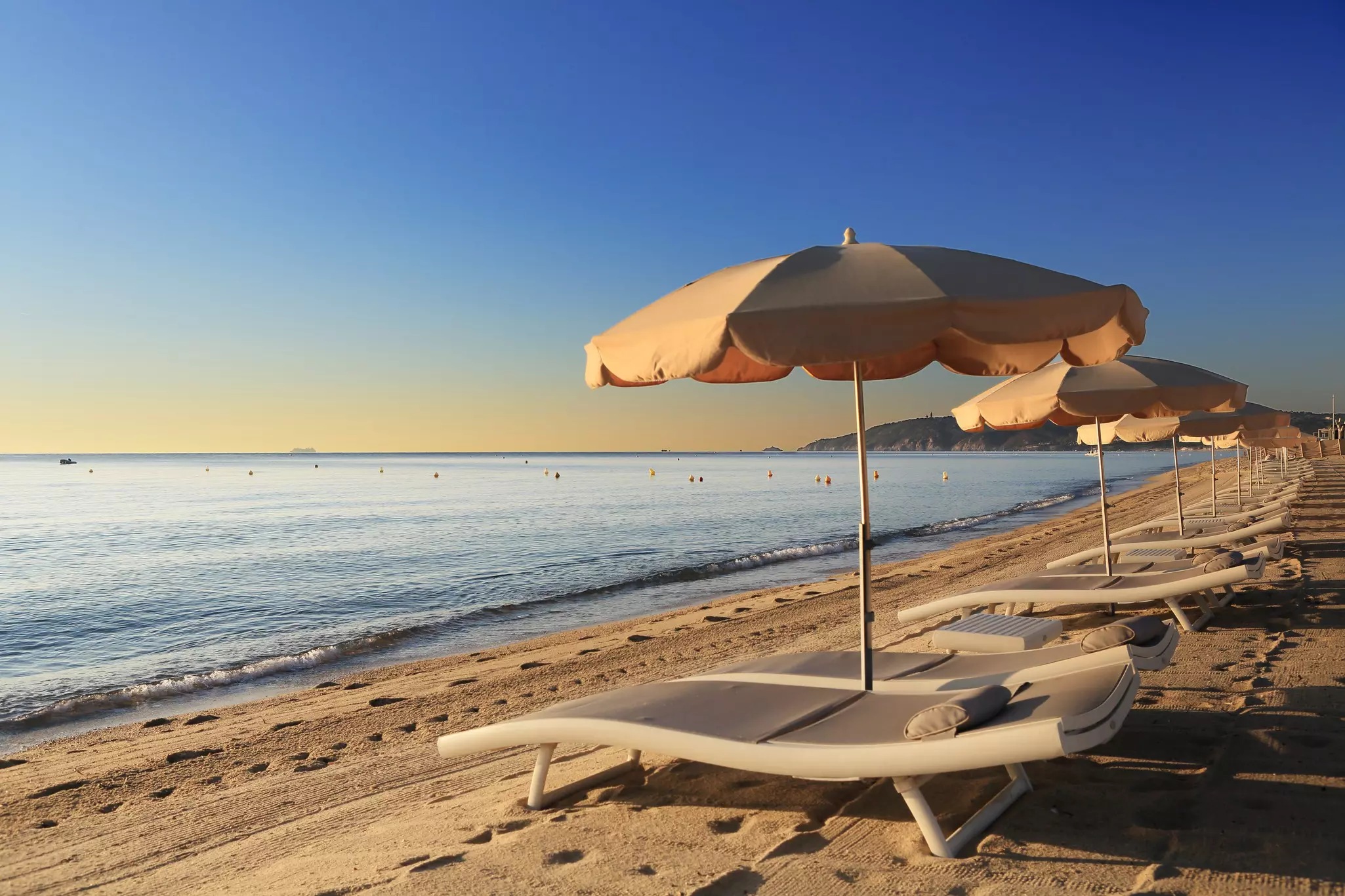 Empty sunloungers and umbrellas lined up on a sandy beach