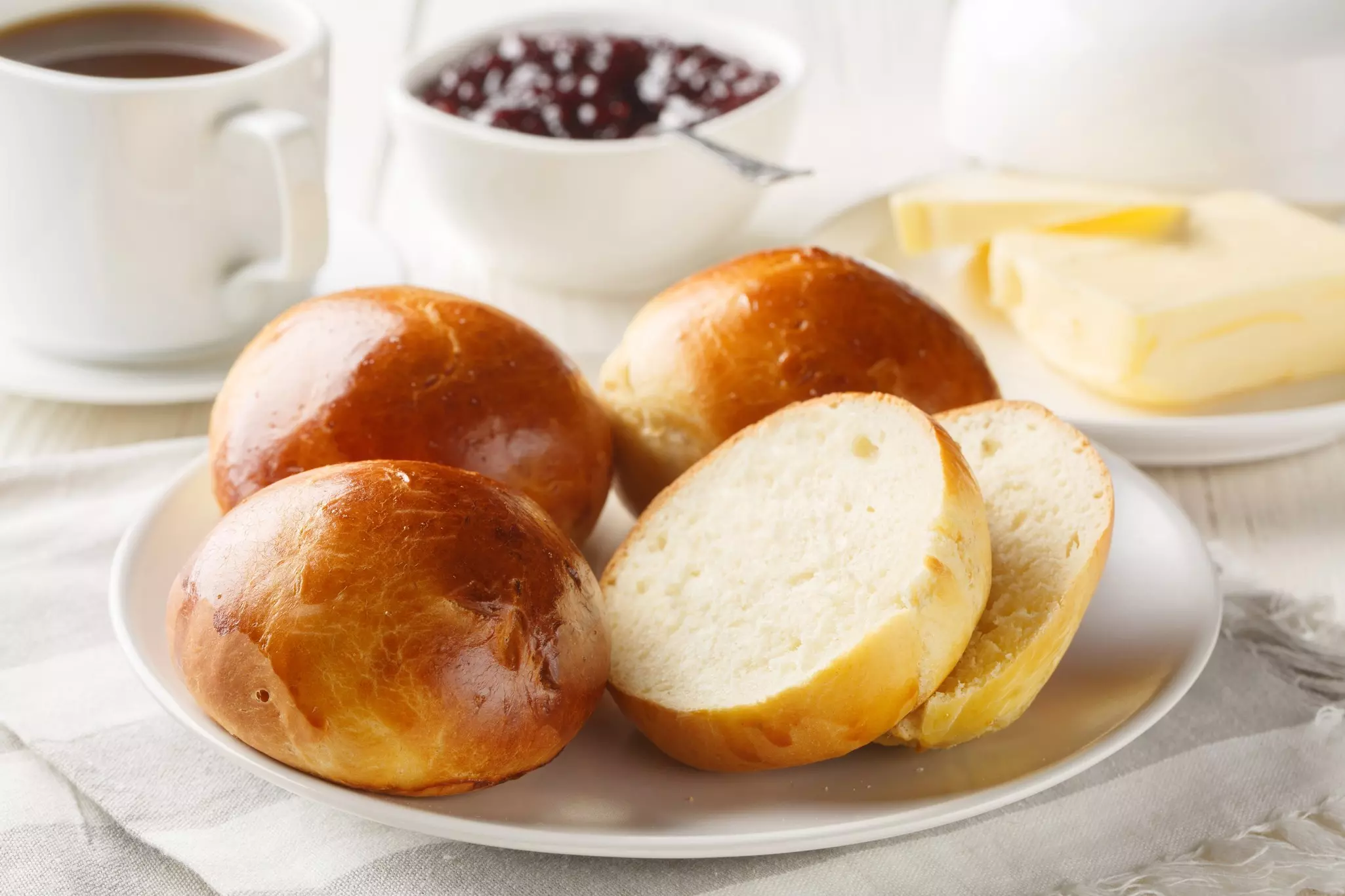 Soft and Delicious Norwegian Boller Cardamom buns served with butter, jam and coffee closeup on the wooden table.