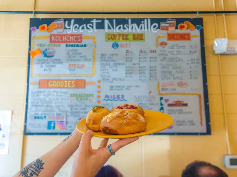 Kolaches at Yeast, held up in front of the menu written on the wall