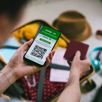 Young woman using digital passport app on mobile phone for travel during COVID-19 Portishead1 GettyImages-1318045190 rfc.jpg