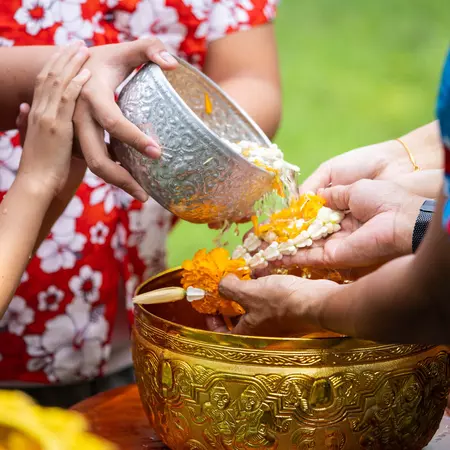 Close up of younger family members pouring scented water over the hands of their elders.