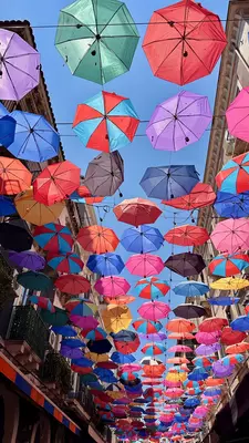 Umbrellas in many colors hang over a street in Italy.