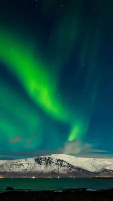 Aurora Borealis displaying over the snowcapped Mount Esja near Reykjavik, Iceland.