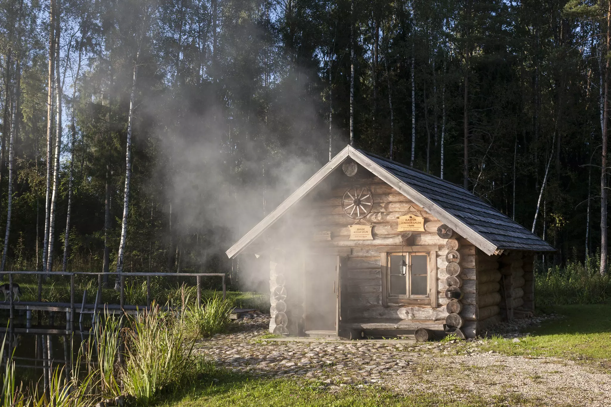 A small wooden cabin with smoke and steam coming out the open door.