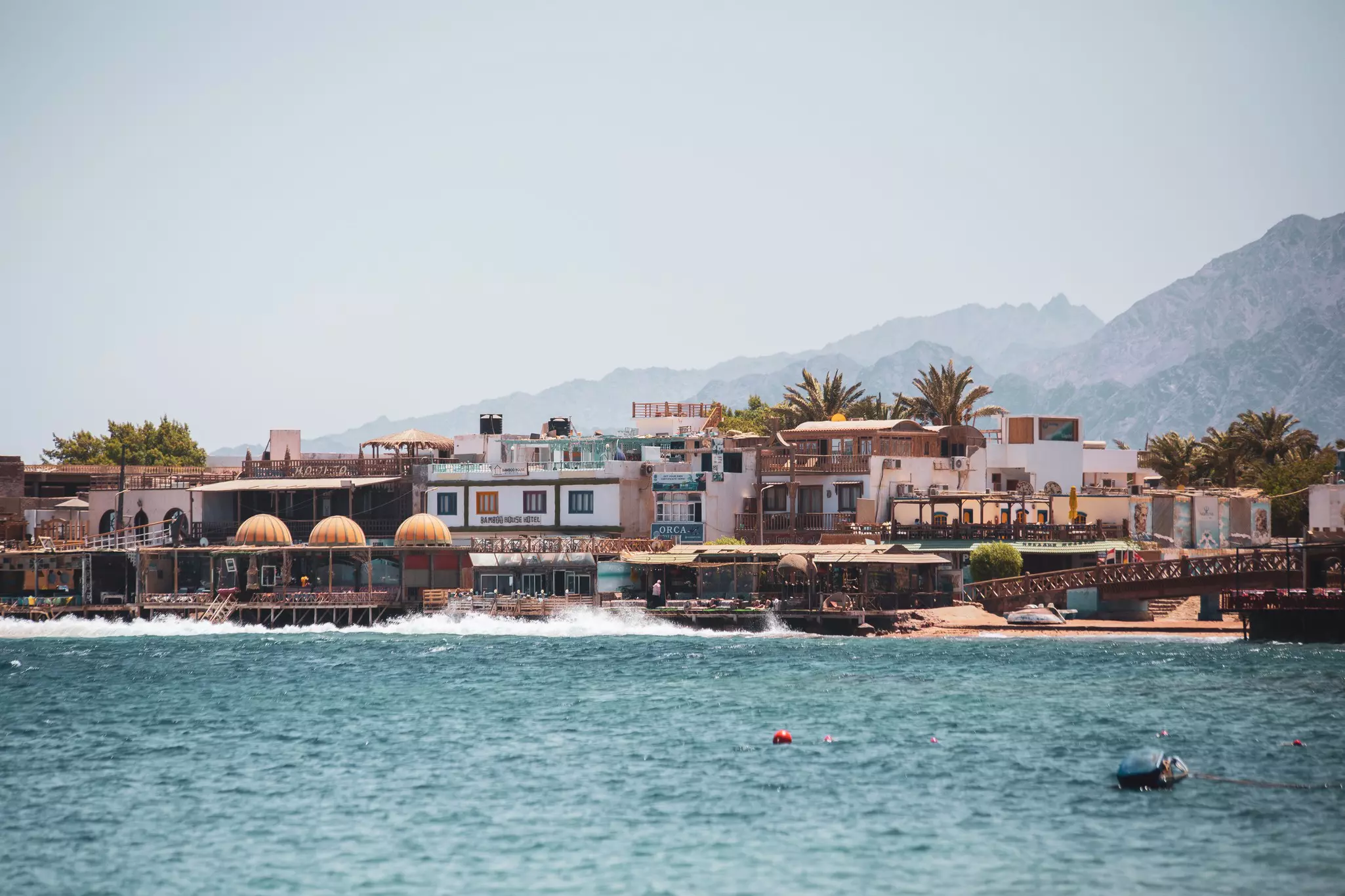 A row of low-rise cafes and restaurants built right to the edge of the sea.
