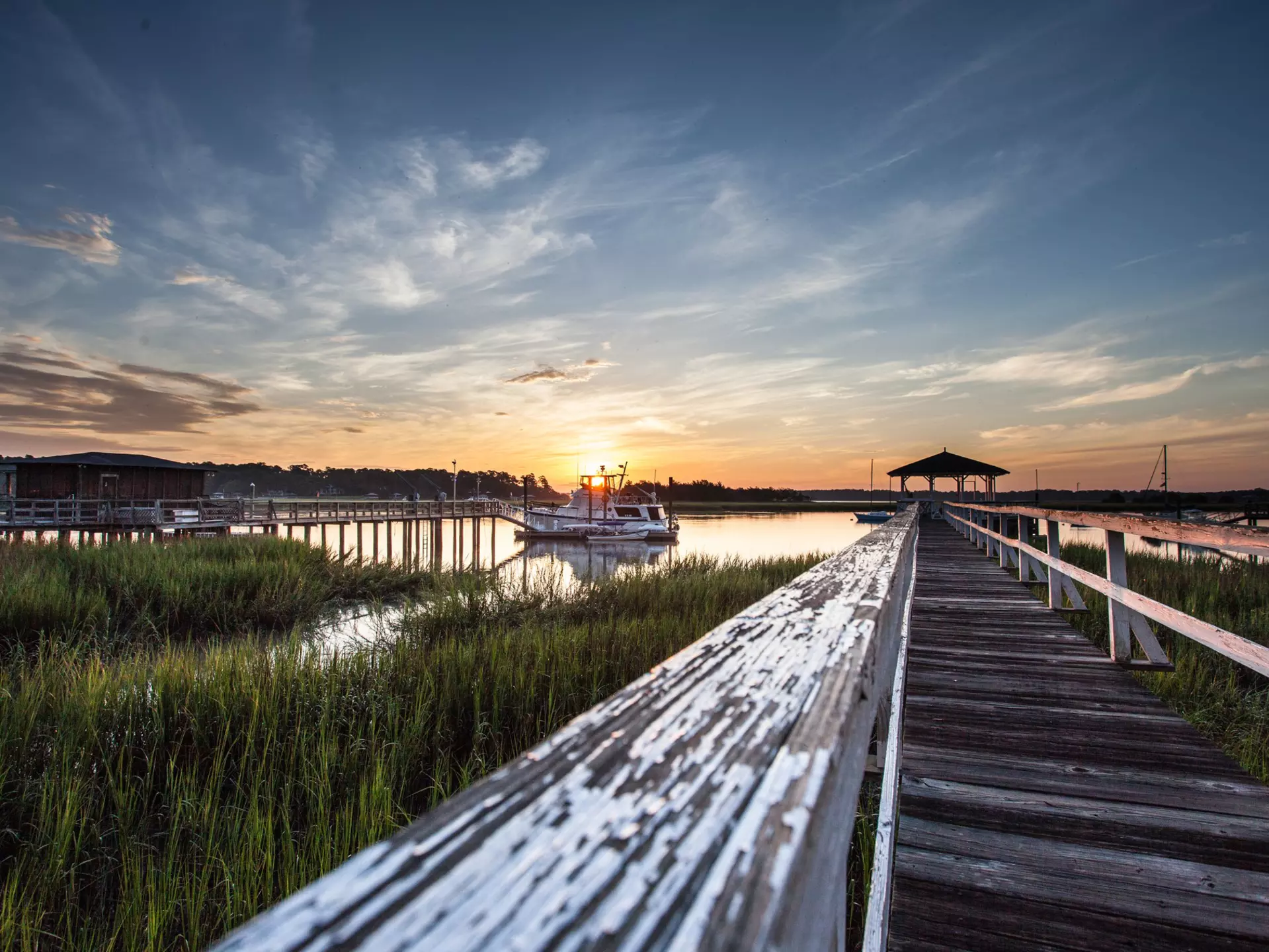 Old wooden dock leading to a beautiful sunrise over the marsh in Savannah, Georgia, Dai Mar Tamarack / Shutterstock