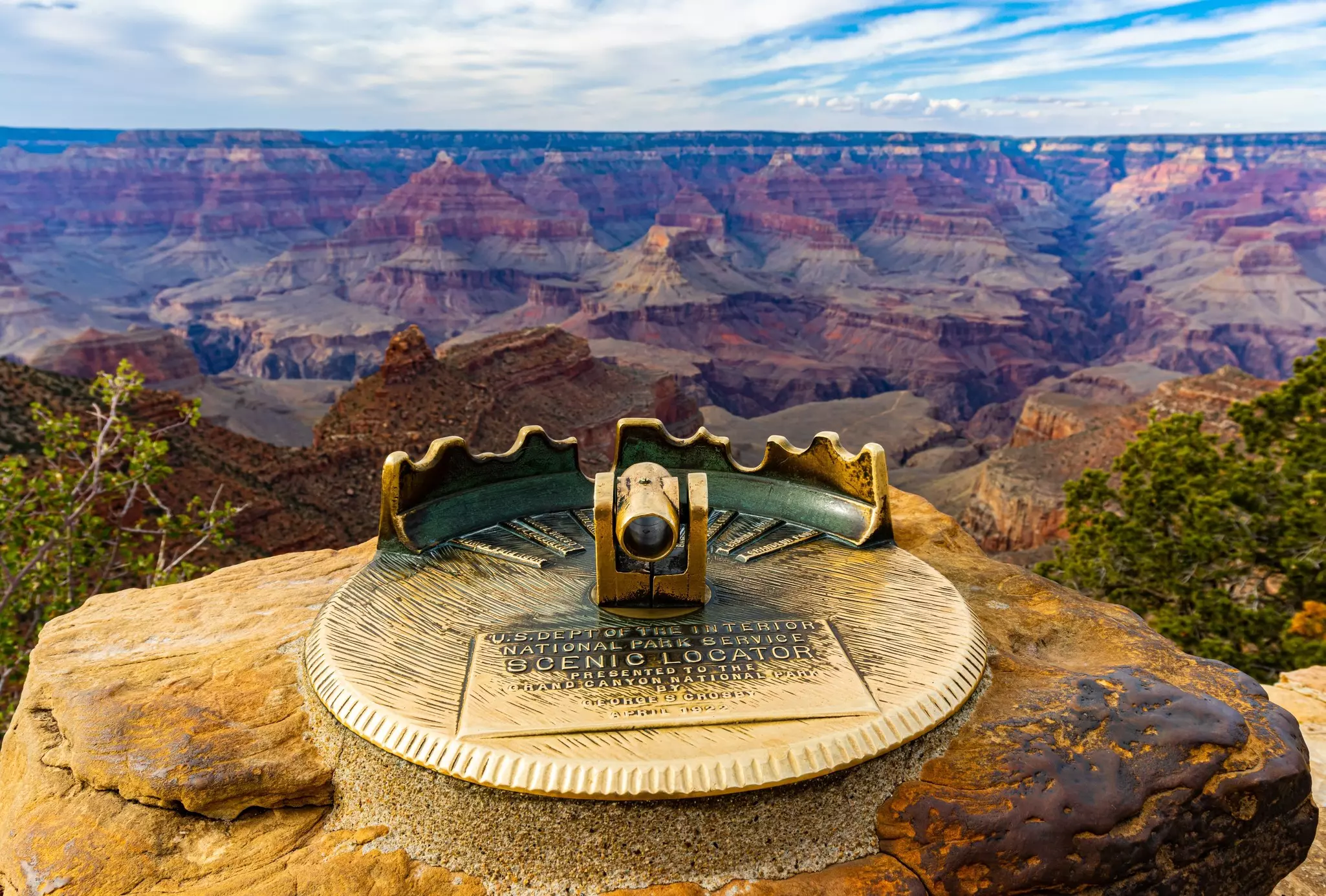 A scenic locator with an eye glass facing towards a vast canyon that stretches into the distance.