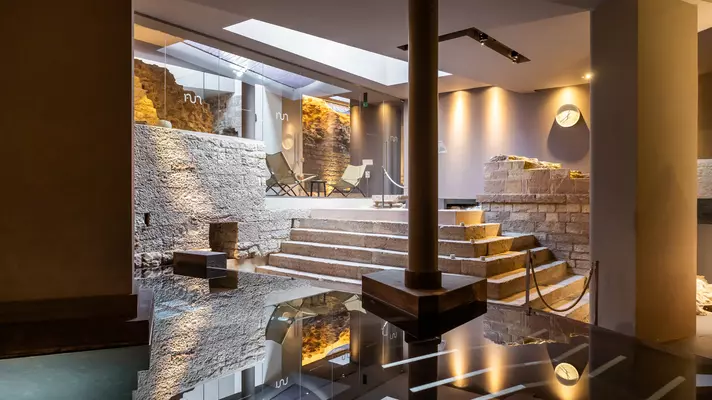 Inside Nun Assisi Spa. A small pool with columns and a seating area up a few stairs.