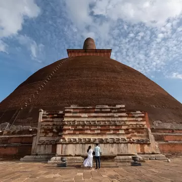 Two people standing in front of the Jetavanaramaya, a Buddhist Stupa located in the ruins of Jetavana in the ancient city Anuradhapura, Sri Lanka.